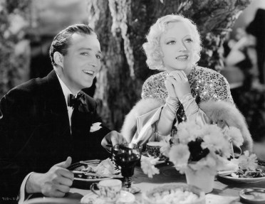 Bing Crosby and Marion Davies sit at table in a scene from the film 'Going Hollywood', 1933. (Photo by Metro-Goldwyn-Mayer/Getty Images)